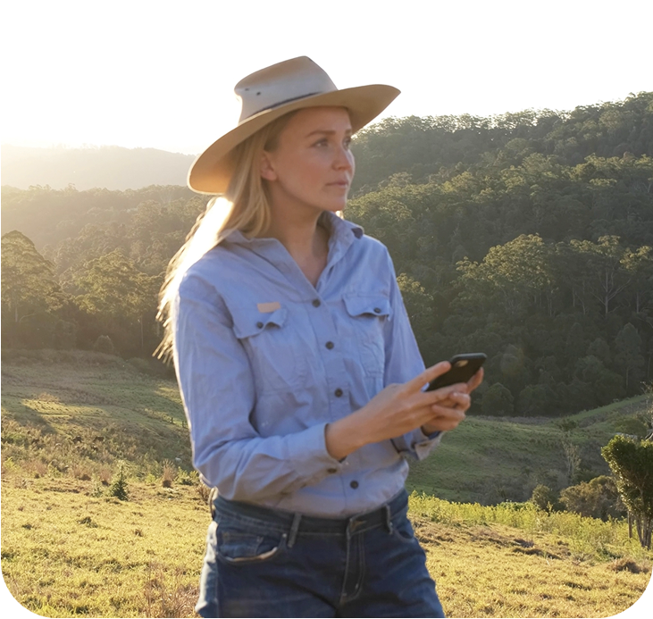 Photo of a woman wearing blue shirt and using a smartphone in a regional outdoor area