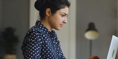 Photo of woman working on a laptop at a desk in a dimly lit home office