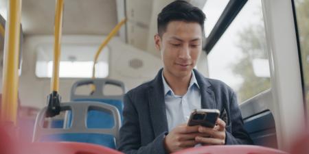 Photo of man sitting on a bus using his smartphone