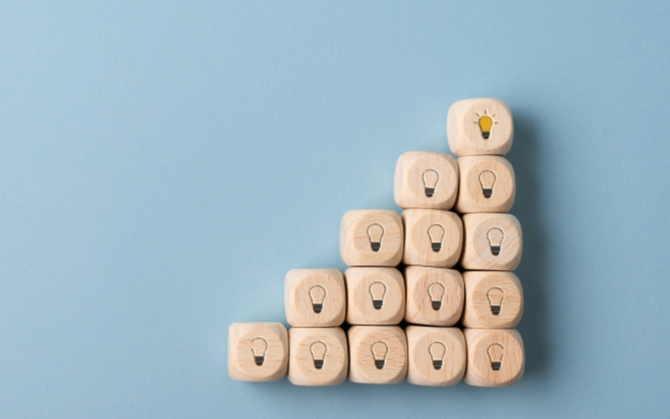 Lit light bulb atop wooden steps, symbolizing innovation and idea progression | Test and Buy Innovation | Digital NSW