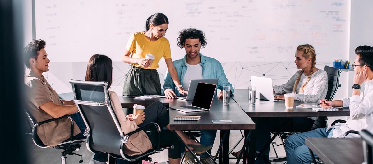 Photo of a group of people in a office meeting with their laptops