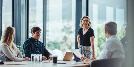 4 people standing smiling around a meeting table | Digital NSW