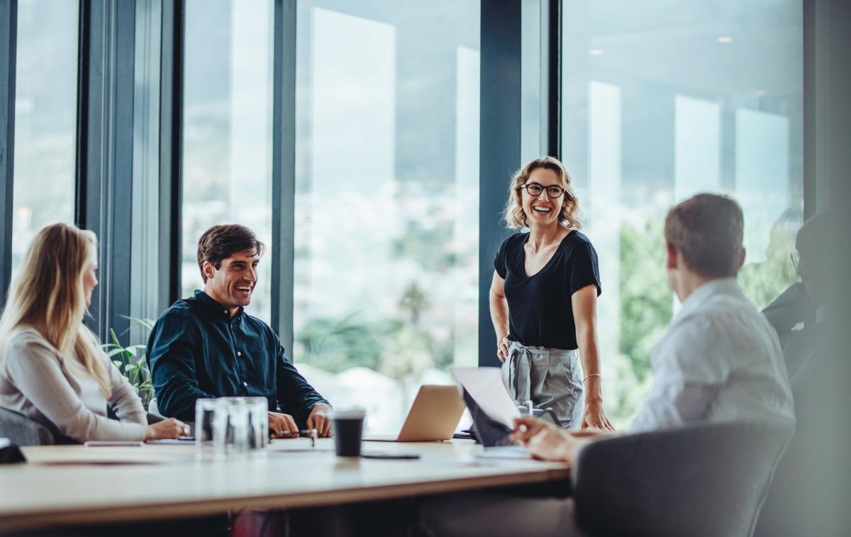 4 people standing smiling around a meeting table | Digital NSW
